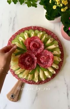 a person is cutting up some fruit on a table with flowers in the bowl behind them