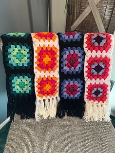 three crocheted granny afghans sitting on top of a chair