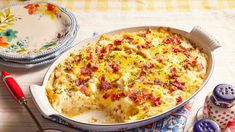 a casserole dish with bacon and cheese in it on a table next to other dishes