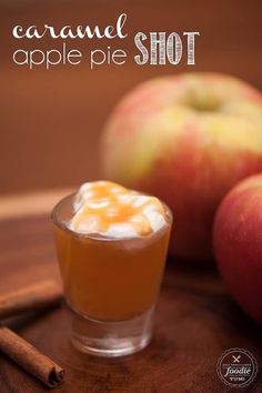 caramel apple pie shot in a glass with cinnamon sticks on the side and an apple next to it