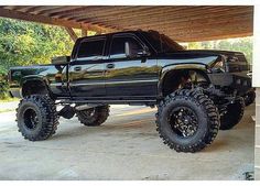 a large black truck parked under a wooden structure