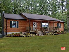 a small log cabin sits in the middle of a grassy area with flowers and trees around it