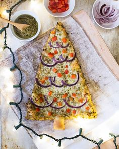 a pizza sitting on top of a wooden cutting board next to bowls of sauces