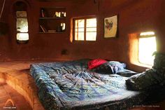 a bed sitting in the middle of a room next to two windows with sunlight streaming through them