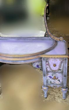 an ornate blue and gold dressing table with mirror on the top, in front of a wall