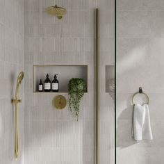 a white tiled bathroom with gold fixtures and shelves on the wall, along with a towel rack