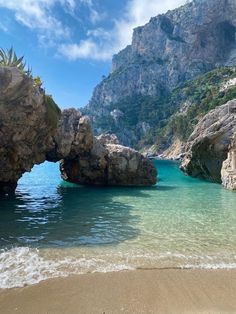 the water is crystal blue and there are rocks in front of it that look like an arch