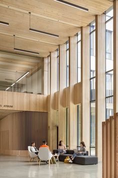 people are sitting in the lobby of an office building with wooden walls and flooring