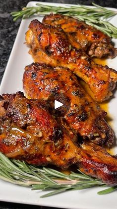 grilled chicken wings with rosemary garnish on a white plate