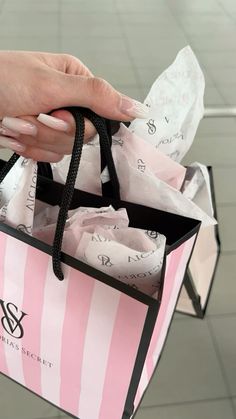 a woman's hand holding a pink and white striped shopping bag with black handles