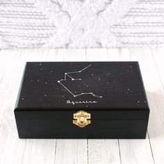 a black box sitting on top of a white wooden floor next to a wall with a zodiac sign drawn on it