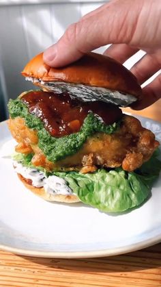 a person is holding up a sandwich on a plate with lettuce and sauce