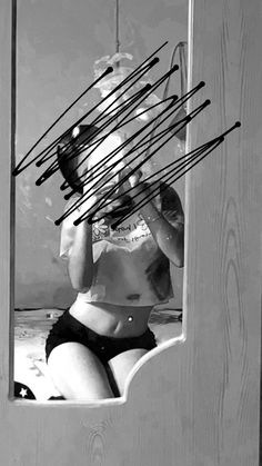 a woman is sitting in front of a mirror with sticks sticking out of it