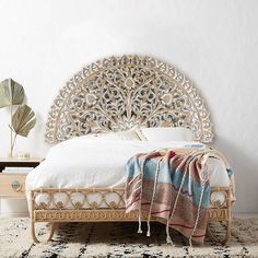 a white bed sitting on top of a rug next to a wooden table and chair