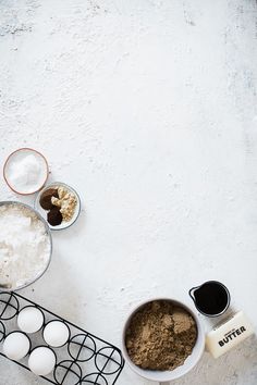 an overhead view of baking ingredients on a white table with eggs, flour and butter