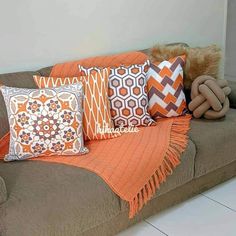 a brown couch with orange and white pillows on it