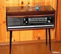 an old fashioned radio sitting on top of a wooden table next to a wood paneled wall