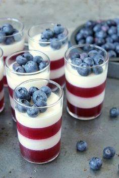 four glasses filled with blueberries and yogurt on top of a metal tray