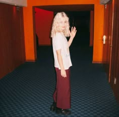 a woman standing in an empty room with her hand up