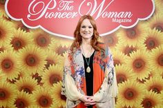 a woman standing in front of a wall with sunflowers