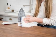 a woman ironing clothes on the kitchen counter