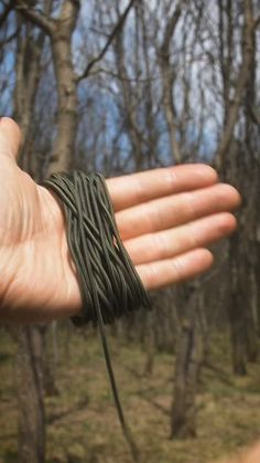 a person holding out their hand with several cords on it in front of some trees