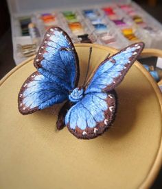 a blue butterfly sitting on top of a yellow chair next to some paintbrushes