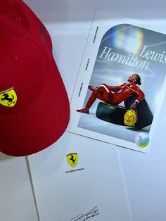 a red hat and book sitting on top of a white table next to a pair of scissors