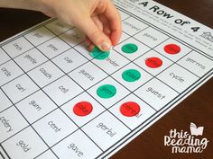 a hand is on the top of a game board with red and green circles in front of it