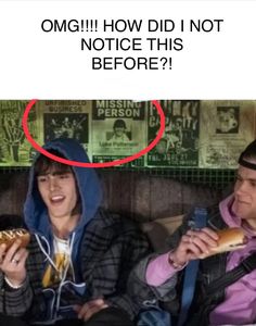 two people sitting on a couch and one is eating a hot dog while the other has a sandwich