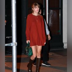 a woman in a red dress is walking down the street