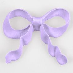 a purple bow shaped object on a white surface with clippings to the side