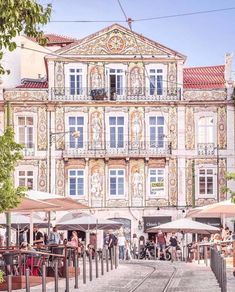 people are walking around in front of an old building with many windows and balconies