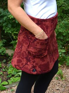 a woman wearing a red and black skirt with pockets on the side is holding an umbrella in her hand