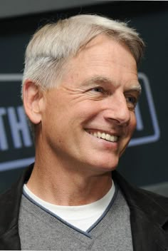 an older man with grey hair smiling at the camera