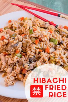 a plate full of fried rice with chopsticks next to it on a table