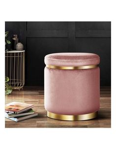 a pink velvet stool with gold trimmings and a magazine on the floor next to it