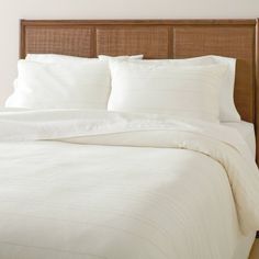 a bed with white sheets and pillows in a bedroom