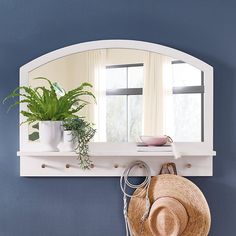 there is a hat, mirror and plant on the shelf