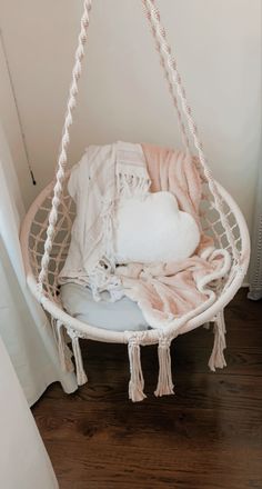 a hammock hanging from the ceiling in a room with white walls and wood floors