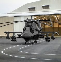 a large helicopter parked on top of an airport tarmac next to a hangar building