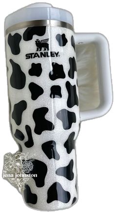 a black and white cow print travel mug with the word stanley on it's side