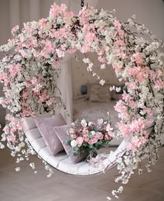 a circular mirror with pink flowers hanging from it's sides in a living room