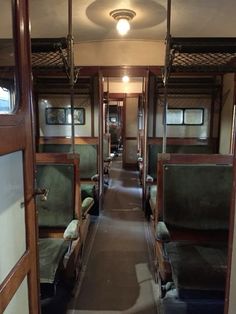 the inside of a train car with green seats and wood trimmings on both sides