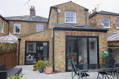 an outdoor patio with table and chairs in front of a brick building on a cloudy day