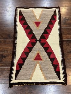 an old navajo rug is laying on the floor with wood floors in front of it