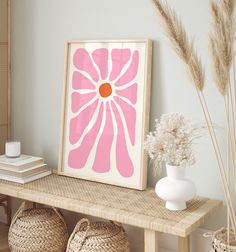 a pink flower is displayed on a shelf next to baskets