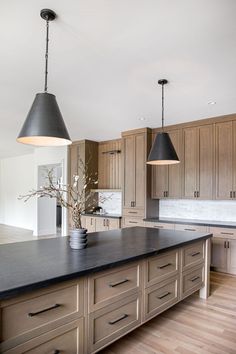 a large kitchen with wooden cabinets and black counter tops, two pendant lights over the island