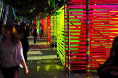 a woman walking down a street next to tall colorful poles