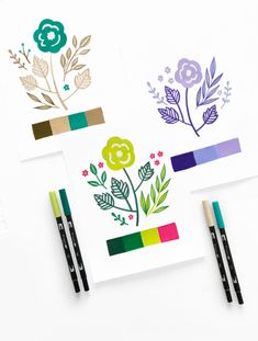 three cards with flowers on them next to two pencils and some colored paper in front of them